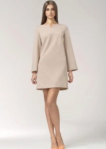 A 60s-inspired short beige dress with a long sleeves and a pair of pumps.